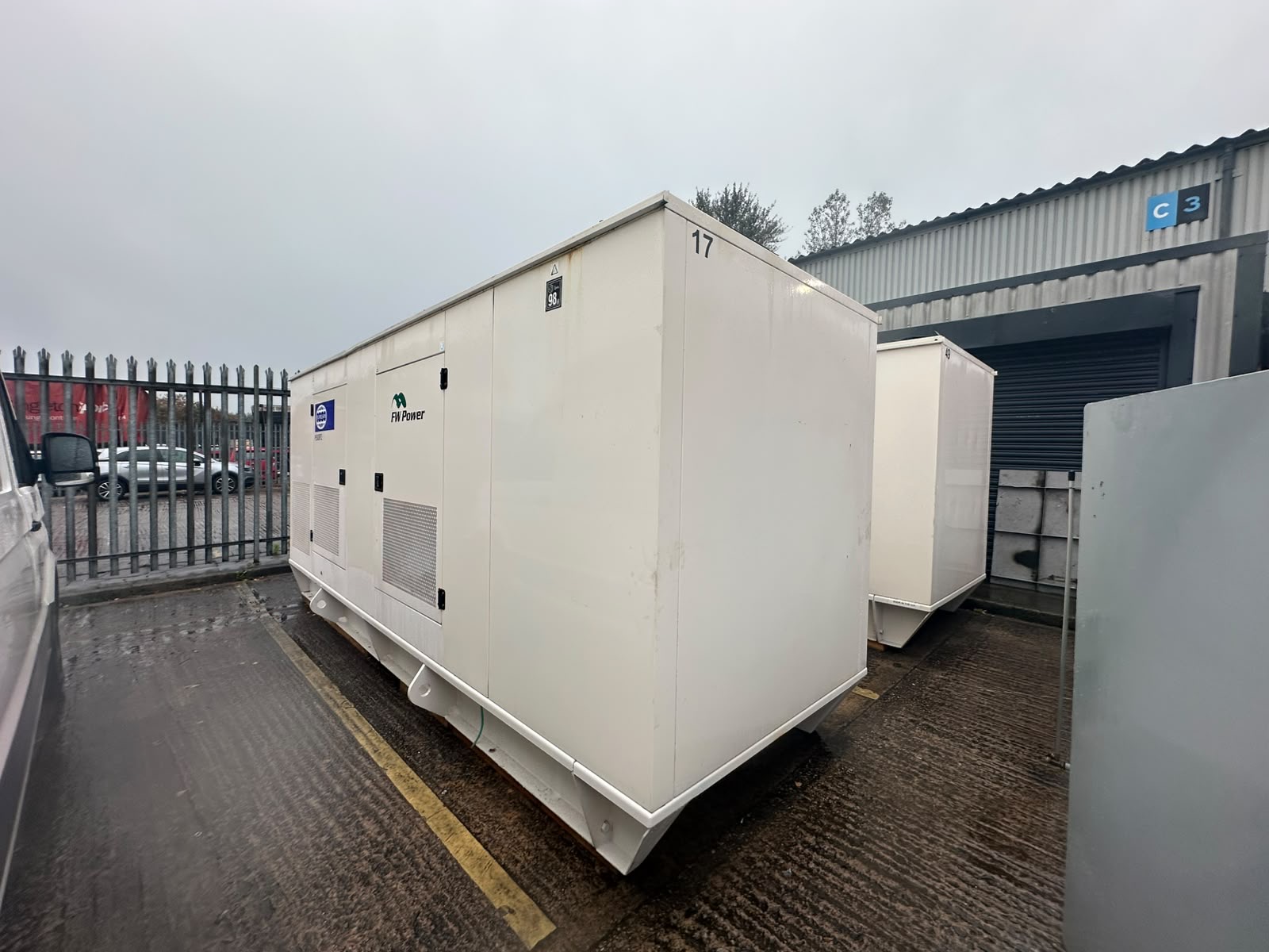 Two acoustic diesel generator enclosures positioned beside the Fire Glass North industrial building.