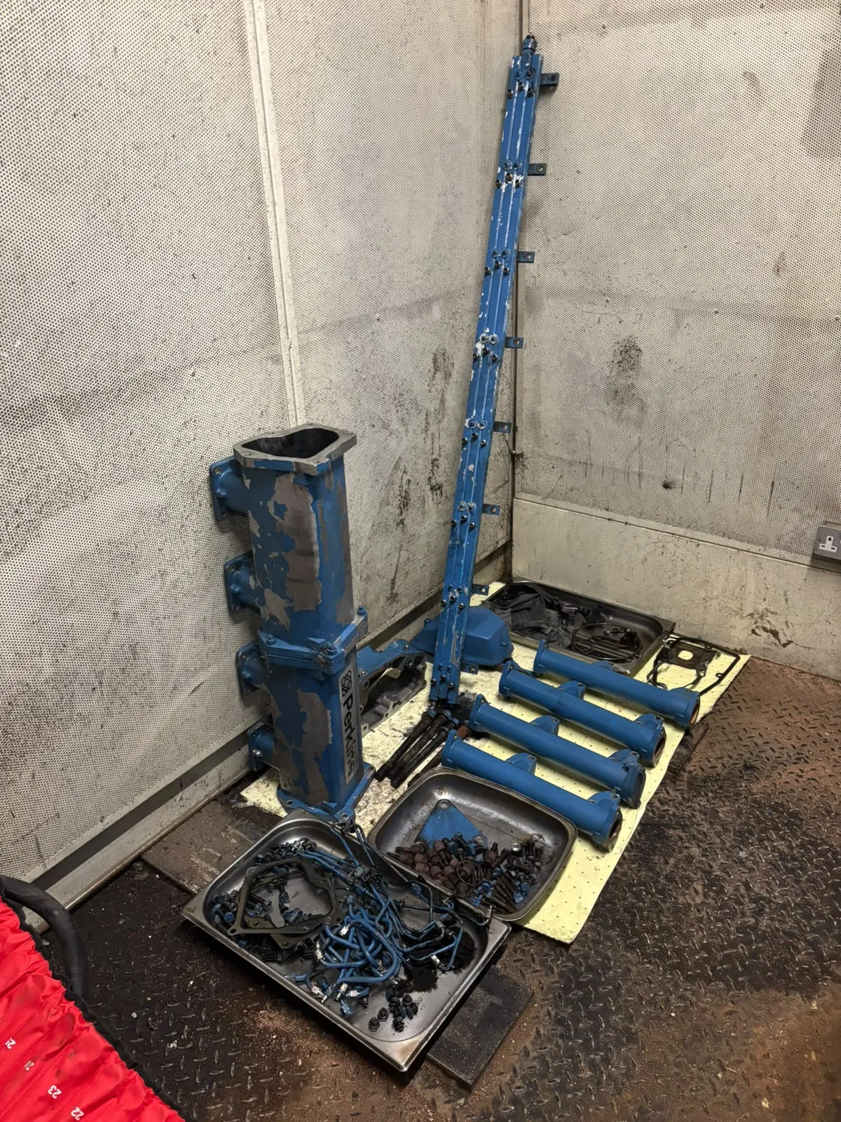 Removed generator engine components and fixings organised in trays beside the generator