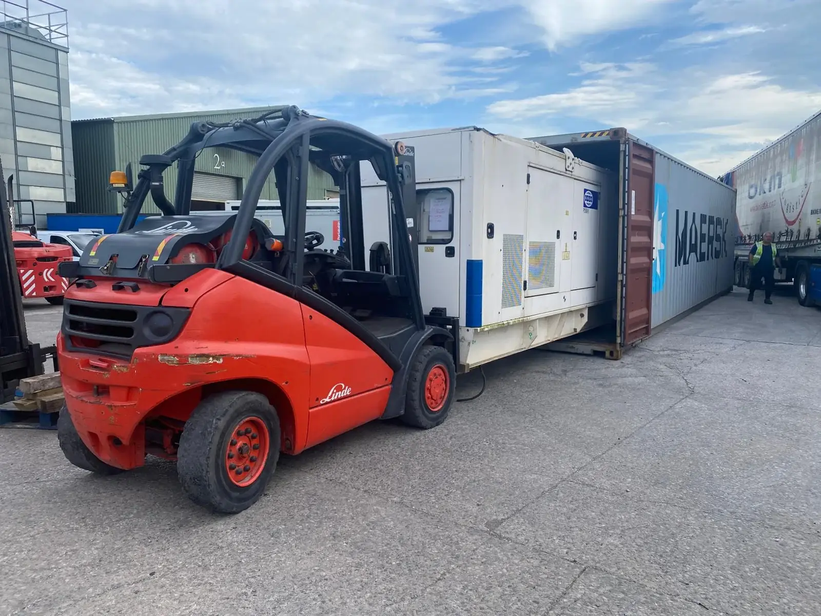 FG Wilson diesel generator being loaded into a shipping container with a forklift