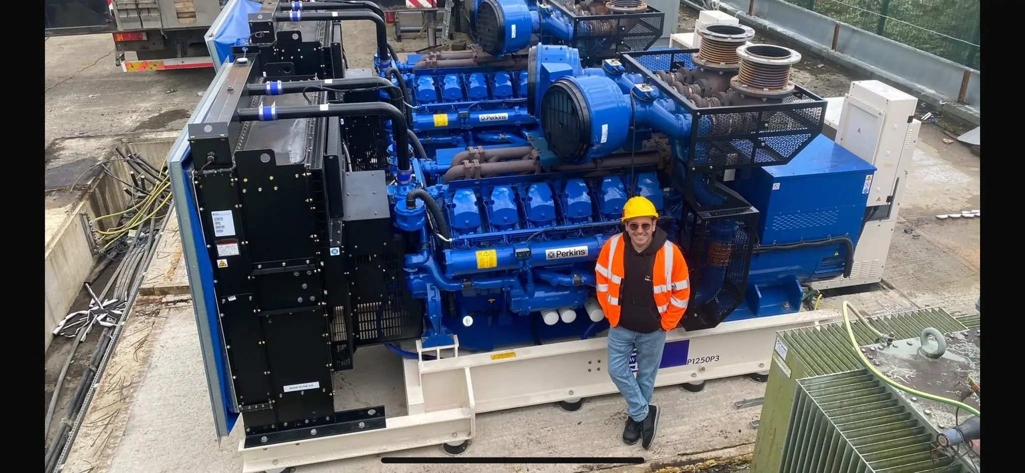 FW Power team member beside large Perkins-powered FG Wilson generators