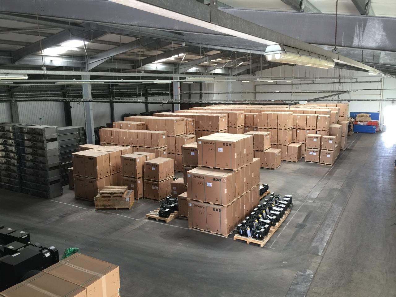 Rows of crated Perkins engines and palletised alternators in a component warehouse