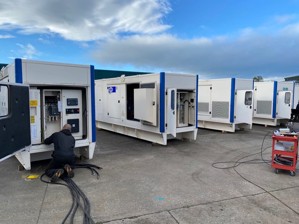 Engineer working beside open control compartments on a line of FG Wilson diesel generators at FW Power